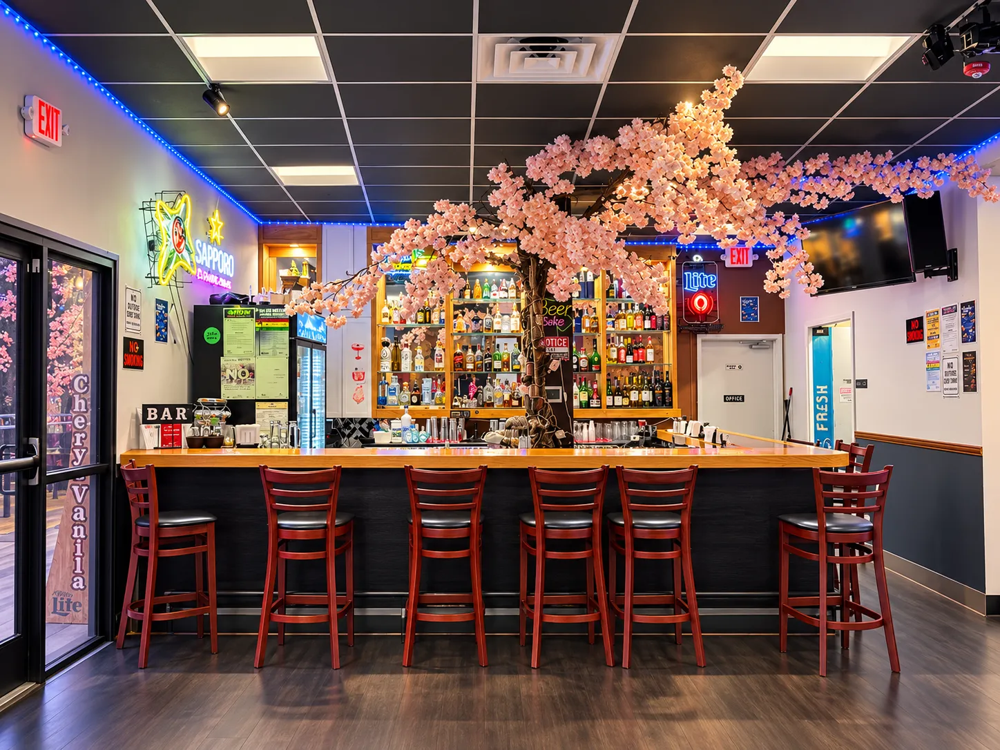 The bar at Swatara Restaurant & Bar under a cherry-blossom tree, with the spirits shelves lit